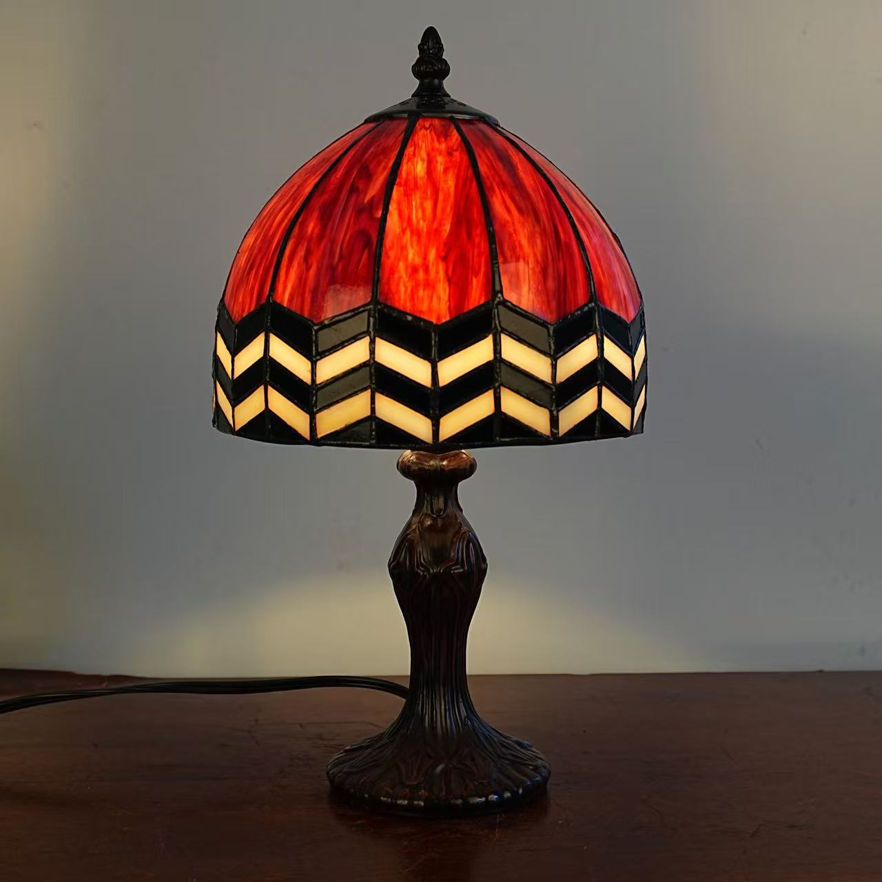 Image 3. Completed Tiffany-style table lamp sample, illuminated front view showing red glass and a light chevron border.